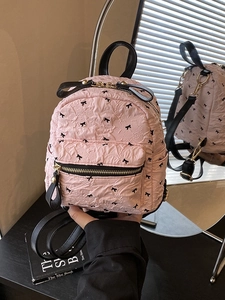 Rosa gesteppter Rucksack mit schwarzen Schleifenmustern und goldenen Metallteilen im Einsatz