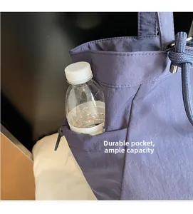 Detail view of durable side pocket on blue canvas tote bag holding a water bottle