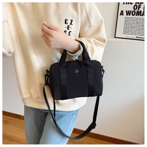Détail du sac Boston en nylon noir avec logo argenté et poignées en sangle tissée noire