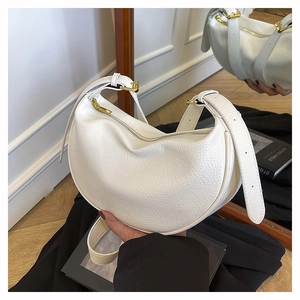 Detail der weißen Mondsichel-Tasche aus Leder mit Lychee-Muster und Goldreißverschluss