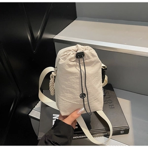 Détail du tissu en nylon beige imperméable et du cordon décoratif de ce sac bandoulière
