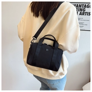 Détail du sac bandoulière en nylon noir avec logo DD en métal et fermeture éclair sur le mannequin