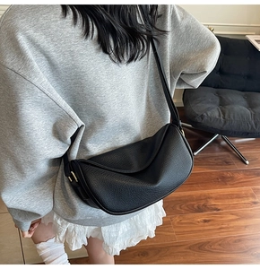 Close-up of black lychee texture leather crossbody bag with elegant gold buckle detail