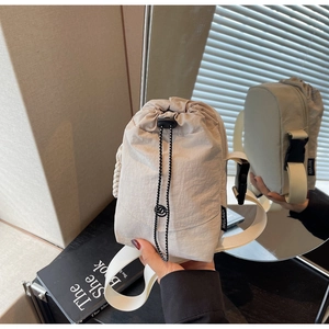 Détail du sac à bandoulière en nylon beige avec cordon de serrage et boucle latérale