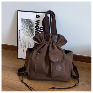 Detail of deep brown canvas travel bag with drawstring closure and vintage round logo