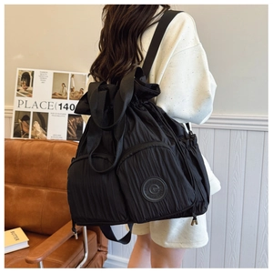Close-up of lightweight black pleated fabric backpack with drawstring closure and logo