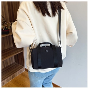 Détail d'un mini sac Boston noir en nylon avec logo métallique et bandoulière réglable