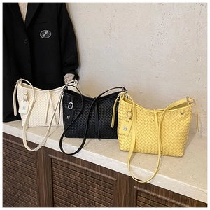 Detail of woven texture shoulder bags in white, black, and yellow with metallic M pendant