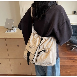 Detail der beigen Nylon-Umhängetasche mit Kordelzugverschluss und praktischer Tasche