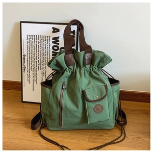 Detail of olive green canvas bucket bag featuring drawstring closure and leather accents