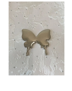Detail of silver liquid metal butterfly charm with high-gloss mirror finish and Y2K style