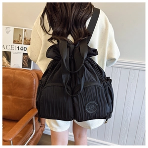 Detail of black drawstring backpack with pleated texture and multiple zipper pockets