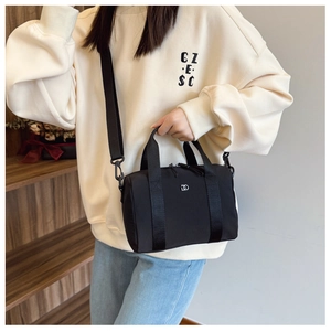 Gros plan du mini sac Boston noir en nylon avec logo argenté porté par un mannequin