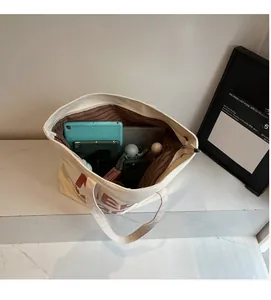 Detailed interior of spacious beige canvas tote bag with brown striped lining and daily items