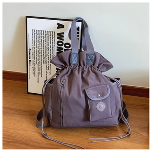 Detail of dark purple canvas backpack with drawstring closure and front zip pockets