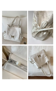 Detail view of cream tote bag with silver butterfly hardware and pearl zipper puller