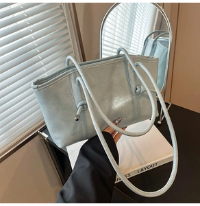 Détail du sac cabas bleu clair en cuir brillant avec bandoulière à nœud élégante