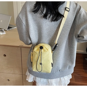 Détail du sac bandoulière jaune en nylon avec cordon de serrage et bandoulière réglable
