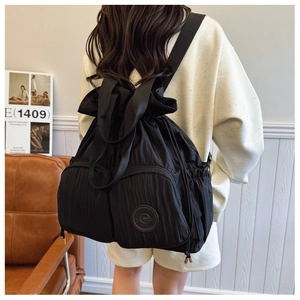 Close-up of black nylon backpack featuring drawstring closure and pleated texture details