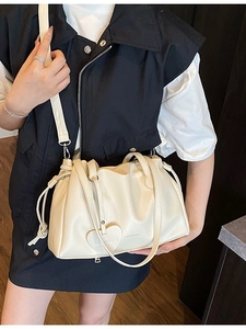Creamy white pleated bucket bag with heart charm and adjustable shoulder strap