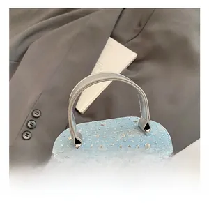 Détail du sac seau en denim bleu clair avec des décorations en strass étincelants