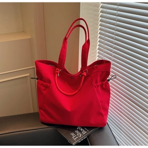 Detail of red large capacity tote bag with side drawstring pockets and durable fabric