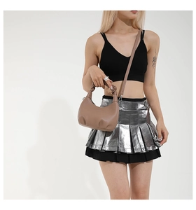 Détail du sac demi-lune marron avec poignée plissée sur un modèle en jupe argent