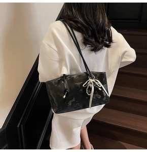 Dettaglio borsa a spalla nera marmorizzata con fiocco e ciondolo a perline elegante