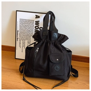 Detail of black drawstring backpack with silver snap pocket and durable nylon texture