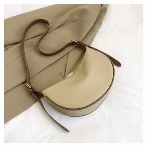 Detail der minimalistischen Halbmond-Tasche mit Lychee-Leder und braunem Kontrastrand