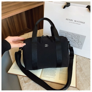 Gros plan du sac Boston en nylon noir avec logo argenté sur des livres d'art
