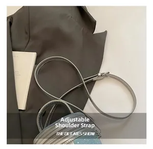 Détail de la bandoulière réglable sur un sac à main seau en denim bleu clair