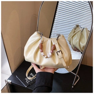 Dettaglio borsa a nuvola beige plissettata con manico in ambra e tracolla riflessa nello specchio