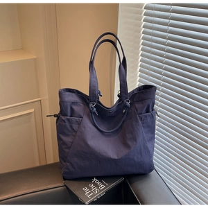 Detail of navy blue nylon tote bag showing adjustable drawstring side pockets and snap closure
