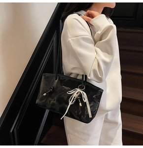 Dettaglio borsa a spalla nera lucida effetto marmo con fiocco decorativo in seta