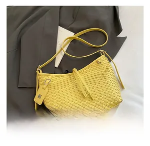 Detail showing yellow woven leather shoulder bag with textured pattern and V-logo tag