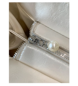 Close-up of pearl white leather tote with silver zipper and large pearl pendant detail