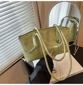 Détail du sac cabas vert avec fines bretelles et finitions de nœuds métalliques élégants