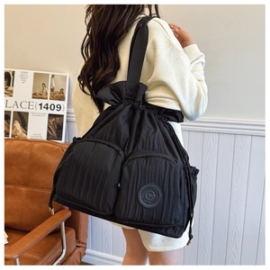 Detail of black pleated nylon shoulder bag with drawstring closure and dual zip pockets