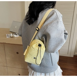 Détail du sac de téléphone en nylon jaune avec cordon de serrage et breloque tissée