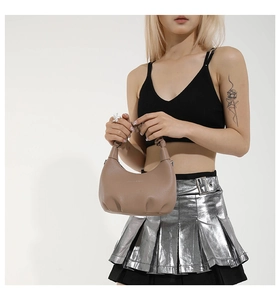 Détail du sac croissant kaki en cuir grainé avec anse plissée porté par le mannequin