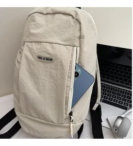 Close-up of beige nylon backpack front zipper pocket holding a smartphone