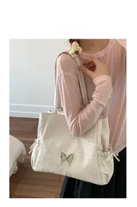 Detail of cream leather tote bag with silver butterfly buckle and sparkling rhinestones