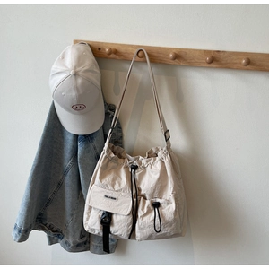 Detail der beigen Nylon-Umhängetasche mit Kordelzugtasche und Schnallen in Lifestyle-Umgebung