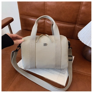 Vue détaillée d'un sac à main beige avec double fermeture éclair et logo sur siège cuir