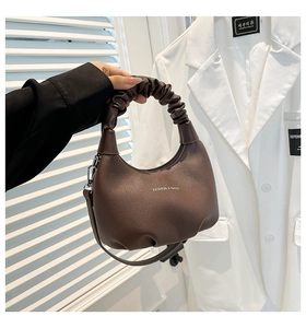 Vue détaillée d'un sac demi-lune marron foncé avec texture grainée et poignée plissée