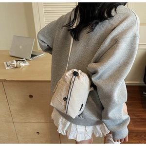 Sac bandoulière en toile imperméable beige avec cordon de serrage dans un décor intérieur