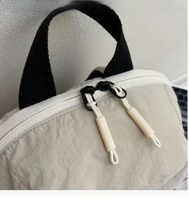 Detailed close-up of the smooth dual zippers on this beige nylon outdoor backpack