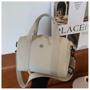 Détail du sac bandoulière en nylon beige avec logo métallique et sangle ajustable