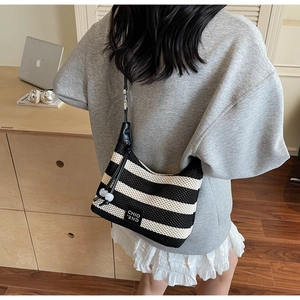 Detail of black and white striped knit hobo bag with leather strap and drawstring closure